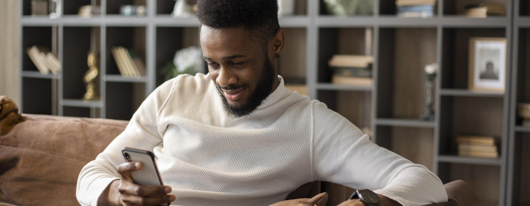 a man sitting on a couch looking at his phone
