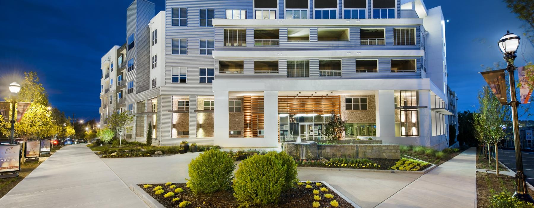 a building with a walkway and bushes in front of it